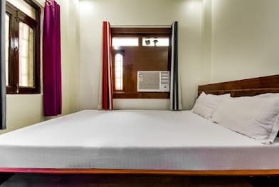 Air-conditioned room at Happy Guest House Bodhgaya with a large bed and a window air-conditioning unit