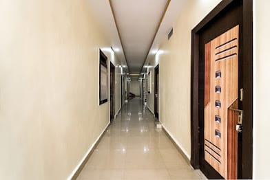 Well-lit tiled corridor leading to guest rooms at Happy Guest House Bodhgaya