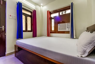 Air-conditioned guest room with blue and red curtains at Happy Guest House Bodhgaya