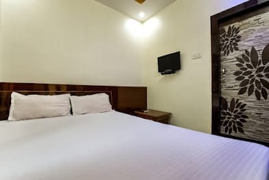 Standard double room at Happy Guest House Bodhgaya with one large bed, wooden headboard and wall-mounted television